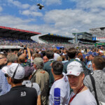 Spot the 'flying' pit lane camera above the grid walk crowd.